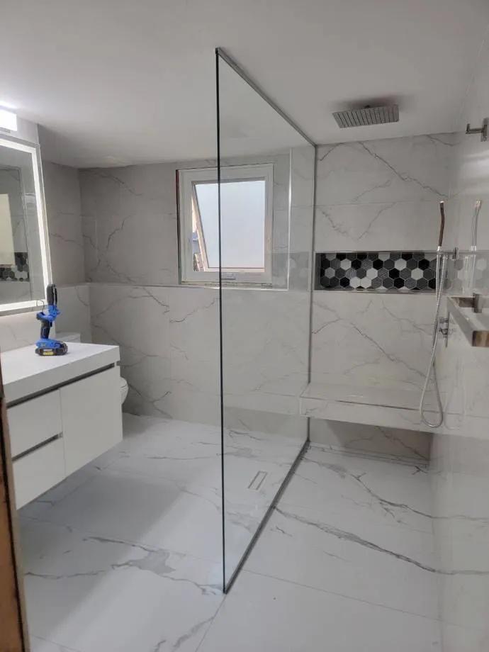 Finished glass-enclosed shower with marble tile and hexagon mosaic niche installed by BBJ Flooring Corp