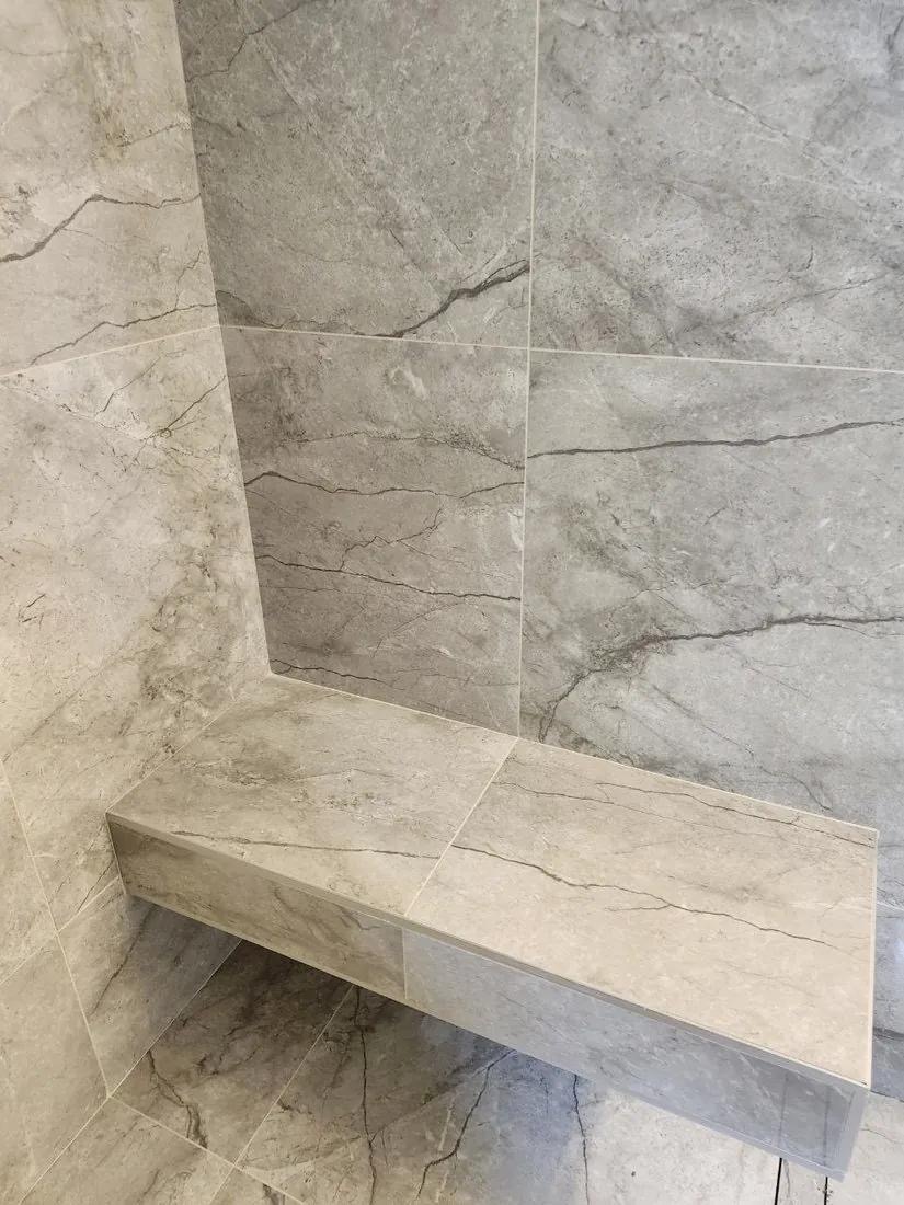 Close-up of a finished marble-look floating shower bench installed by BBJ Flooring Corp