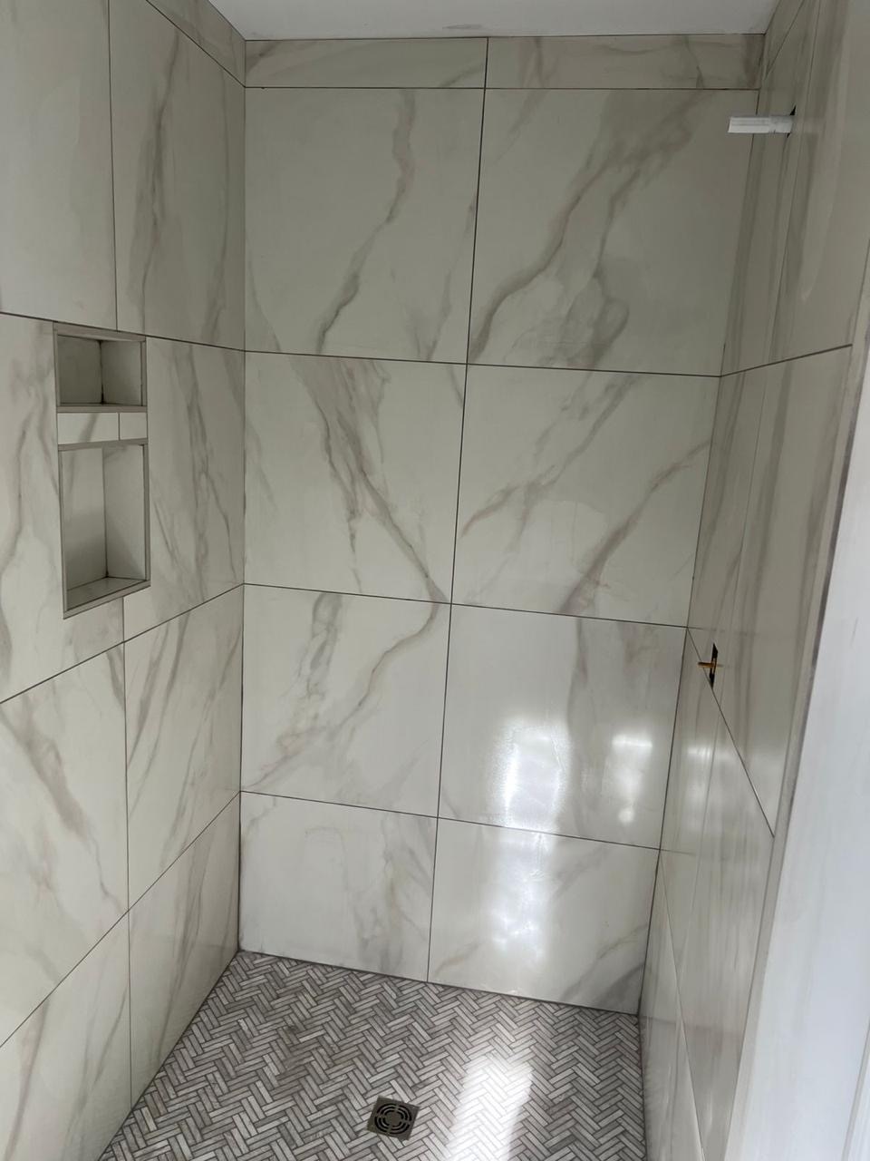 Finished marble-look tile shower with herringbone mosaic floor installed by BBJ Flooring Corp