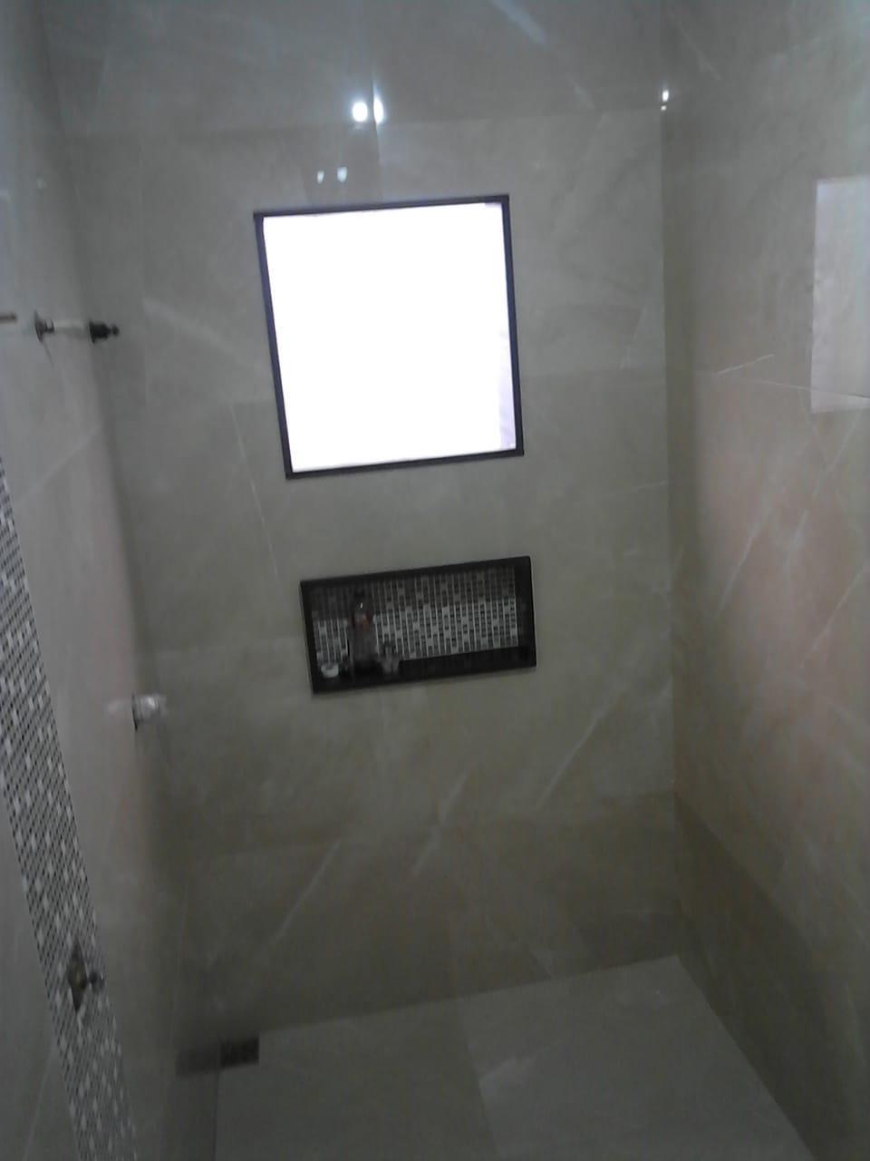 Finished marble-look tile shower with dark mosaic niche installed by BBJ Flooring Corp