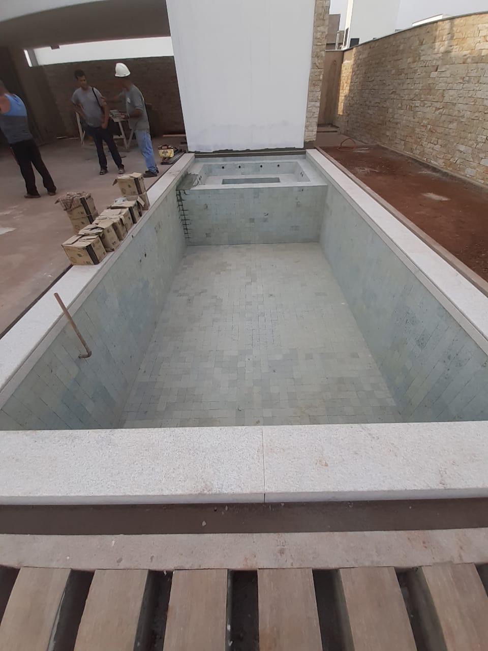 Outdoor pool lined with mosaic tile mid-installation by BBJ Flooring Corp