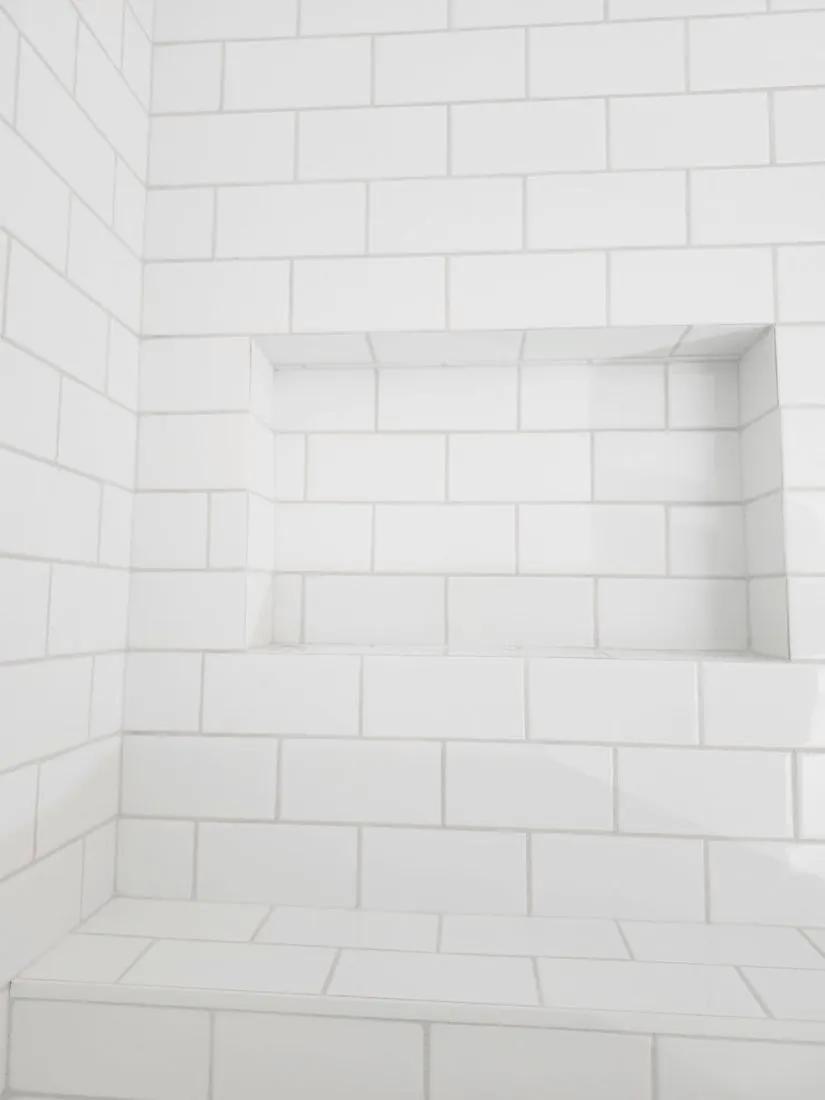 Close-up of a finished white subway tile shower niche and bench installed by BBJ Flooring Corp