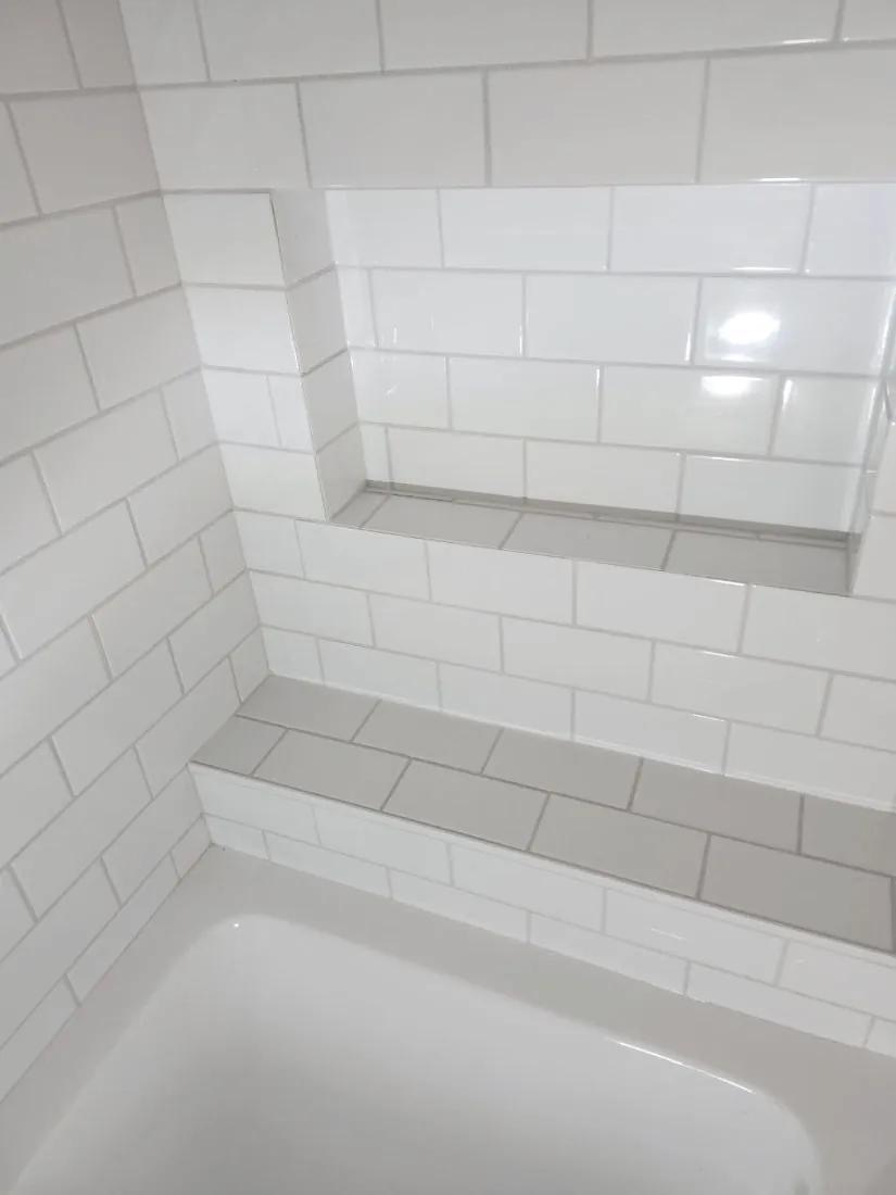 Finished subway tile tub surround with built-in niche and bench installed by BBJ Flooring Corp
