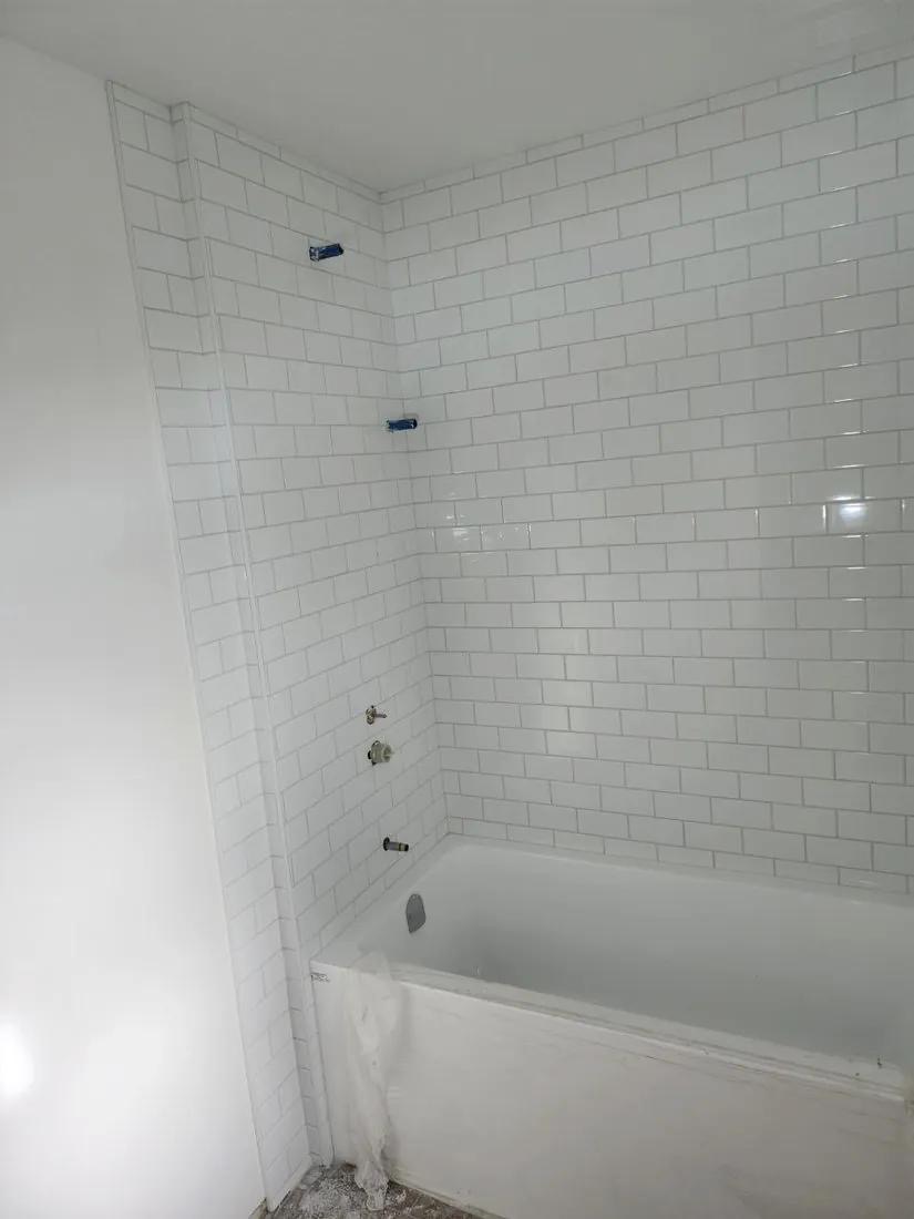 White subway tile tub surround mid-installation by BBJ Flooring Corp